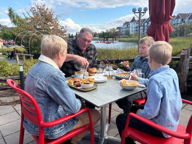 A father and his three young boys seated around a patio dining table, enjoying their meal at Firehall Pizza Co. on a sunny Fall afternoon.