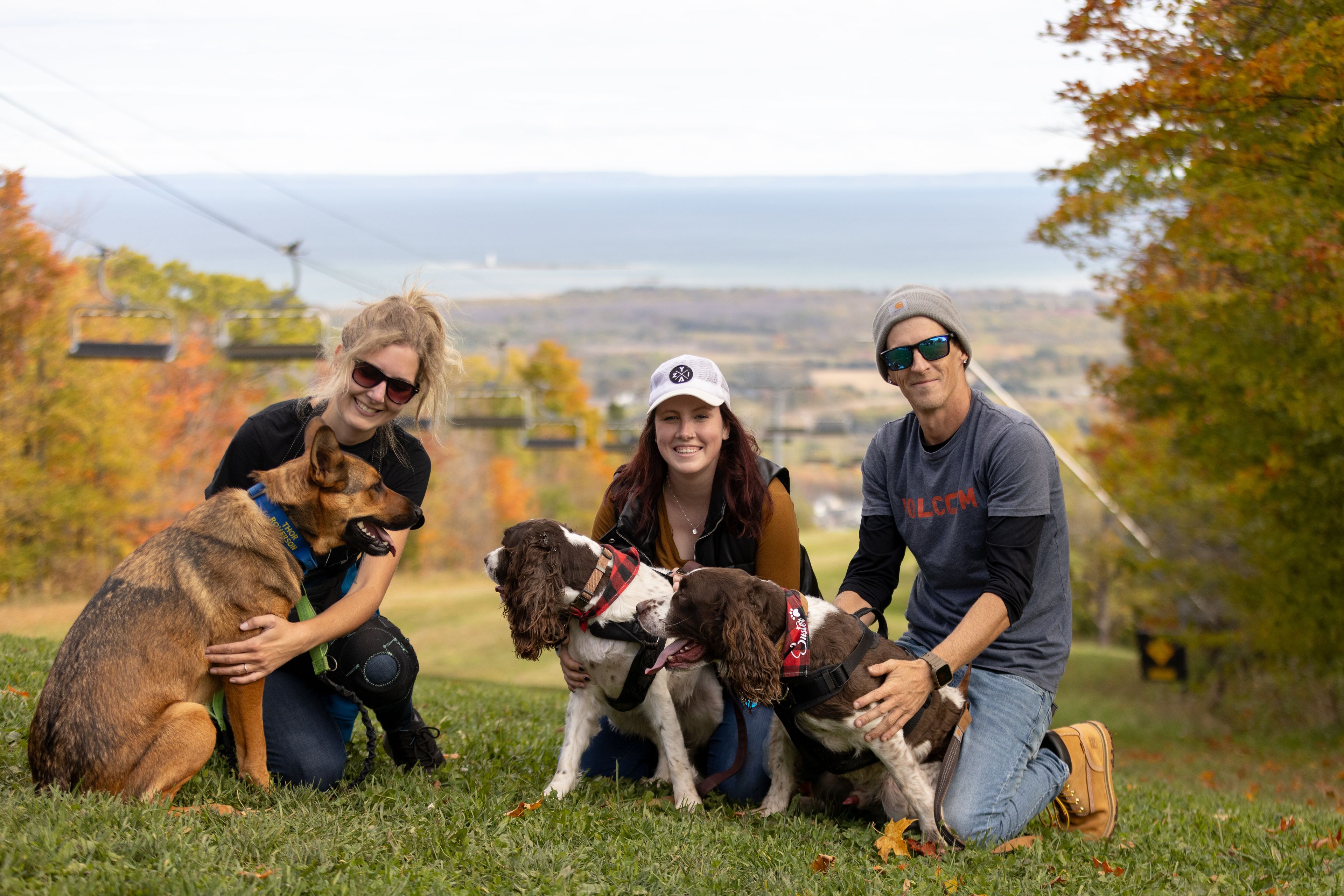 A group of three friends and their dogs smiling for a photo at the lookout on Village Way Hiking Trail on a fall afternoon.