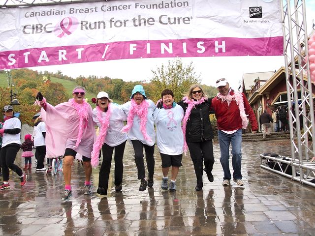 A group of ladies walking with arms wrapped around each other as they cross the finish line together at CIBC Run for the Cure.