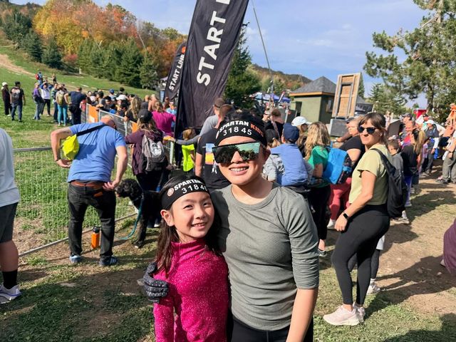 A mom and her daughter smile together at the base of the mountain in celebration of completing the Spartan Trifecta Race at Blue Mountain.
