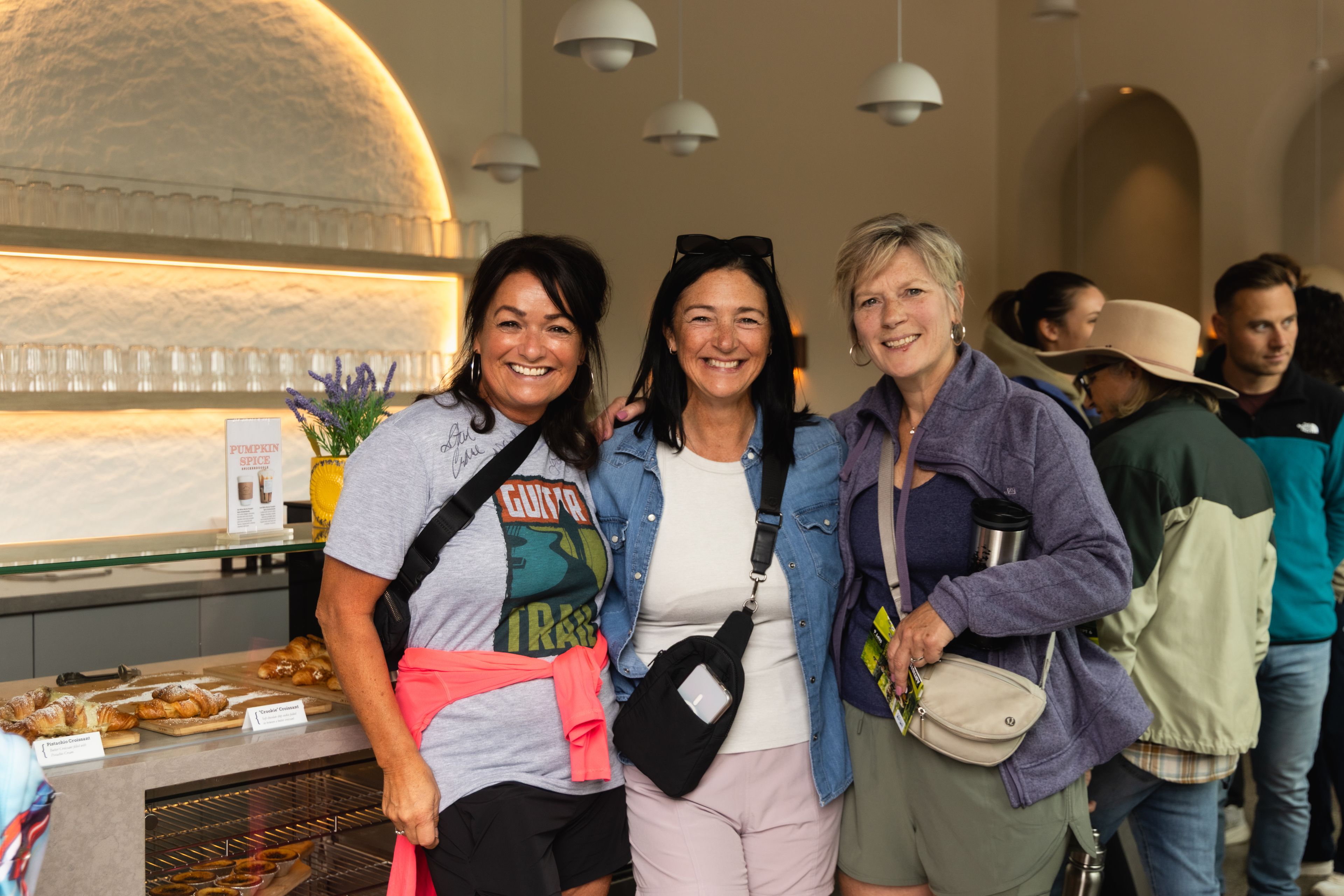 Three smiling ladies gathered at Greekery Café for the Guitar Trail Homeowner VIP event in 2025.