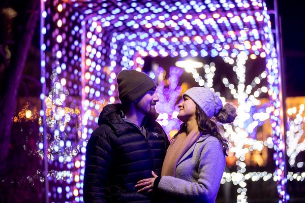 Young couple embracing beneath the glowing Holiday Magic Lights