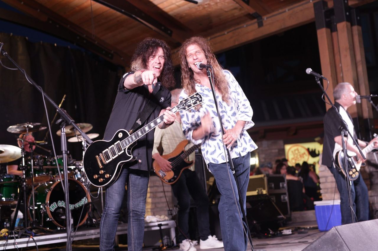 Members of renowned rock band, The Carpet Frogs, smiling and pointing at the camera during a live performance on the Subaru Stage