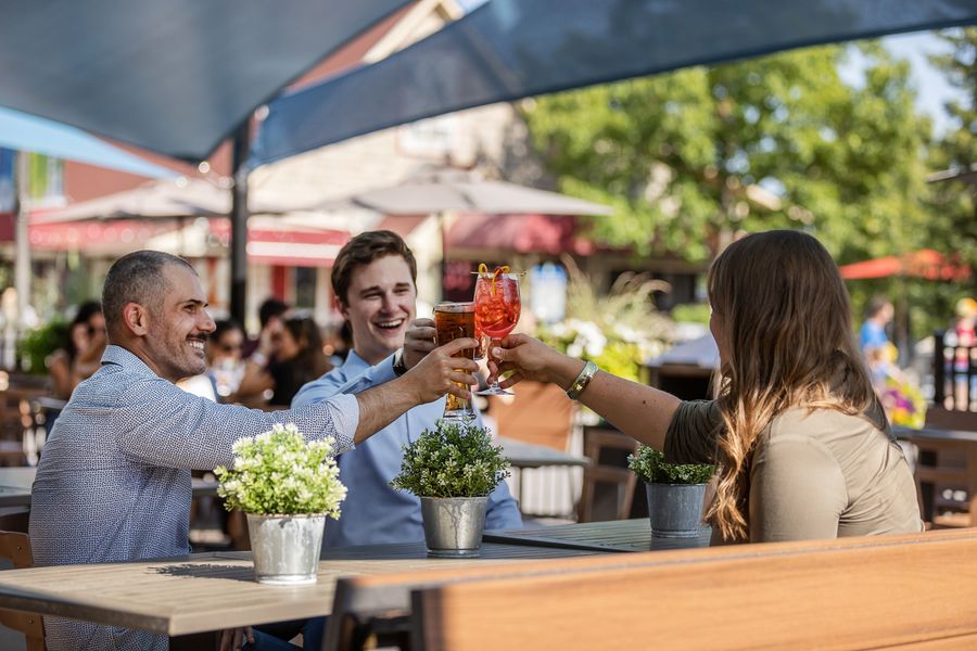 Three colleagues share drinks on Copper Blues Patio. 