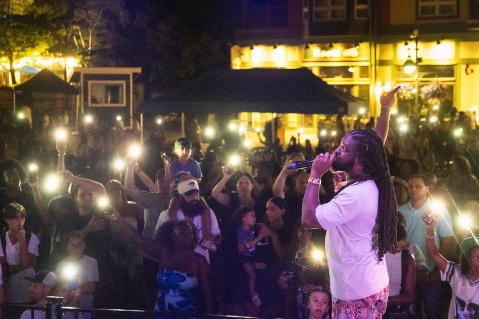 Kirk Diamond performing live on the Subaru Stage in front of an audience holding up the lights on their phones.