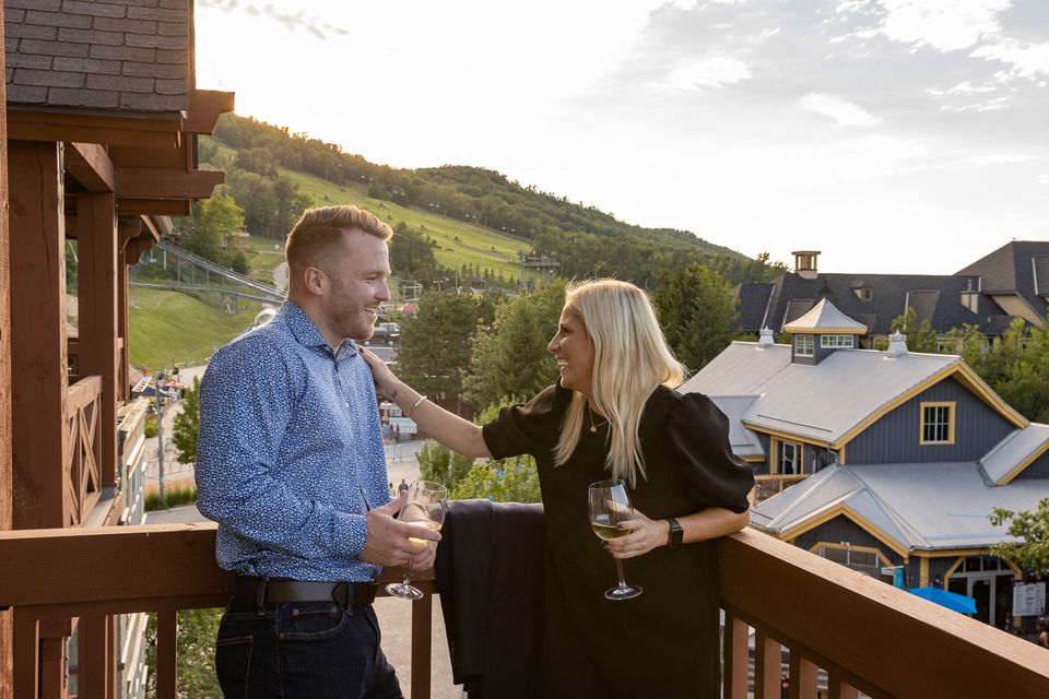 A couple laughs on the patio overlooking the village and the mountain. 