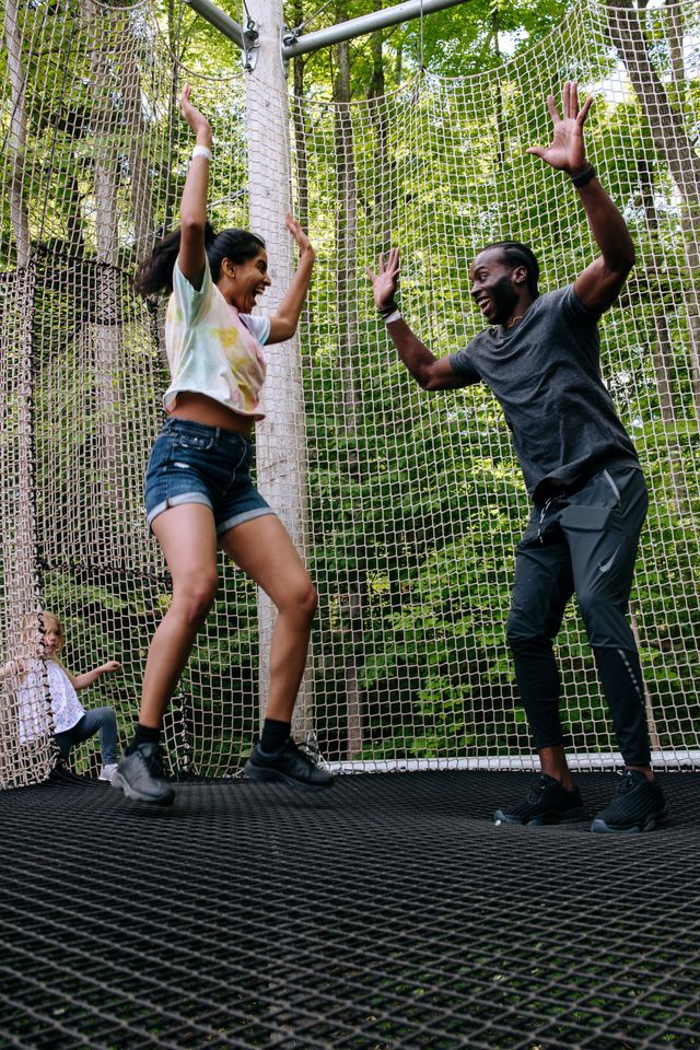 A couple bouncing up from the trampoline floors of the canopy climb adventure in the Blue Mountain Resort Adventure Park.