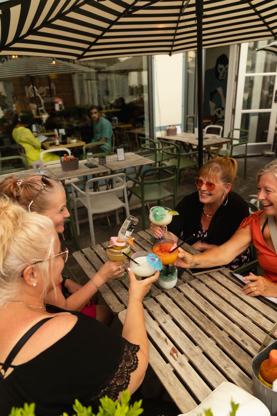 Group of friends clinking their colourful umbrella drinks together on the Camino Taco patio at Blue Mountain Village