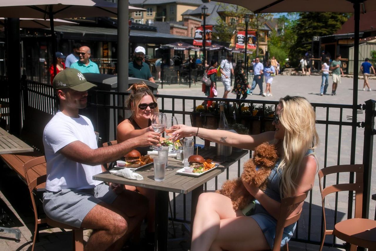 A group of friends enjoying patio drinks on a sunny afternoon at Copper Blues with their dog. 