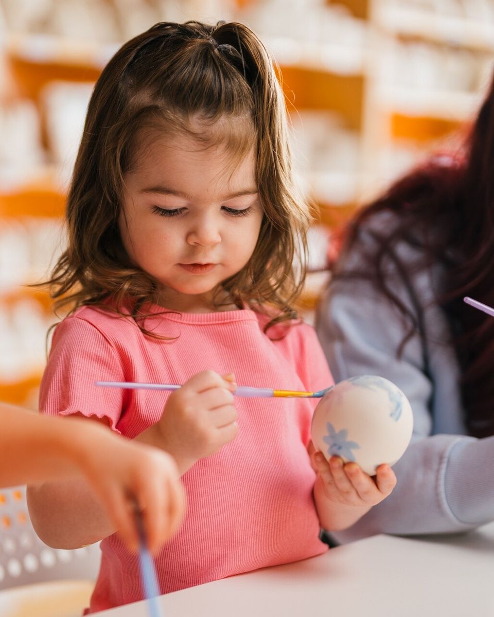 Young toddler painting her own custom clay masterpiece at Crock-a-Doodle Paint Your Own Pottery Studio in Blue Mountain Village.