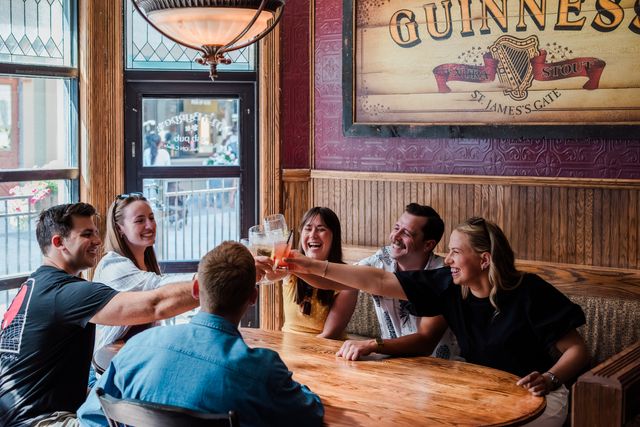 Group of friends clinking their beverages together at MJ Byrne's Irish Pub in Blue Mountain Village