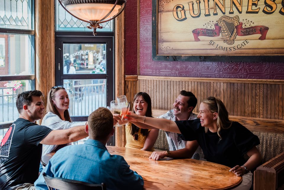 Group of friends clinking their beverages together at MJ Byrne's Irish Pub in Blue Mountain Village