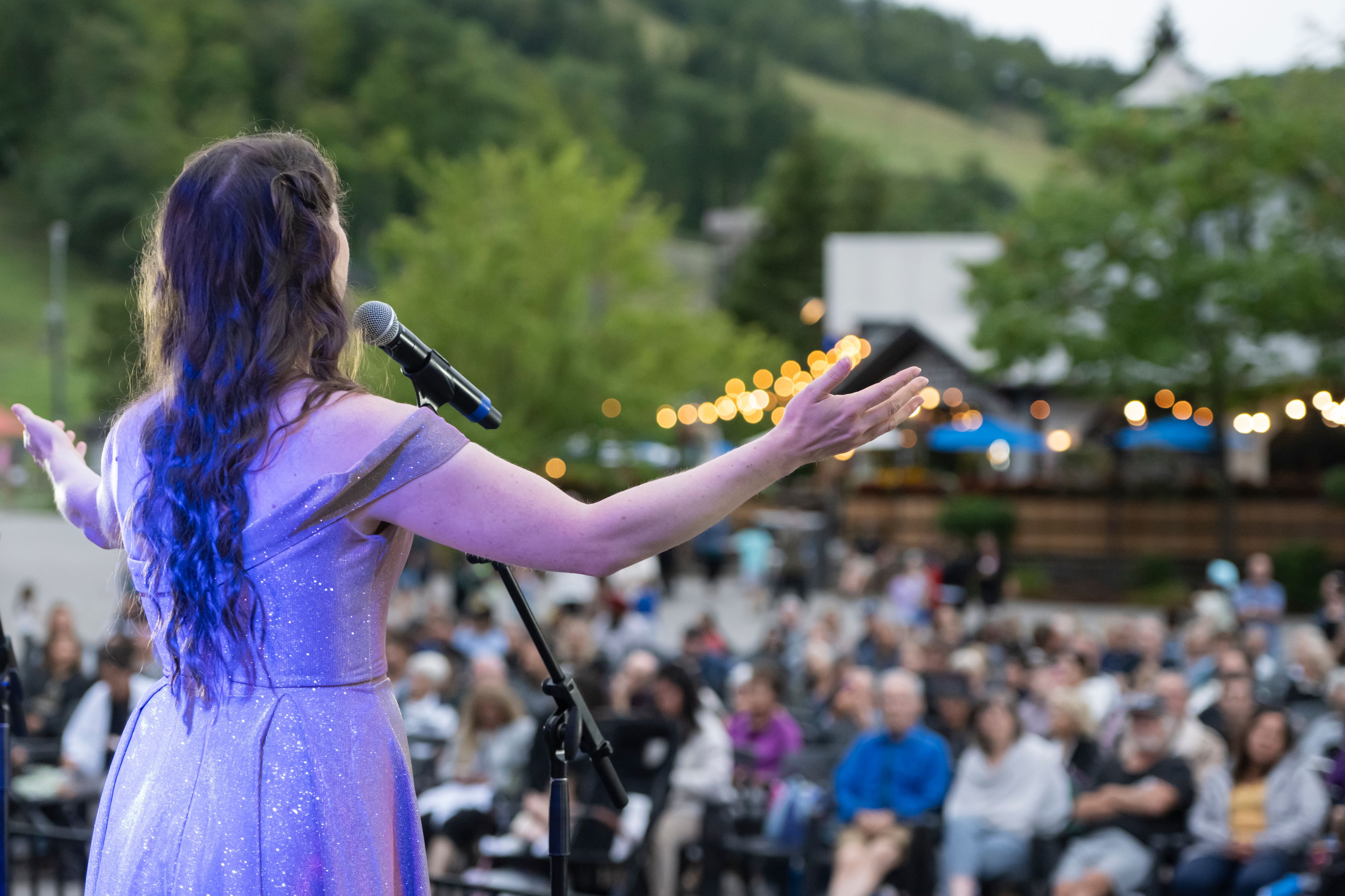 A woman standing on the Subaru Stage, singing classical opera music to the Village audience.