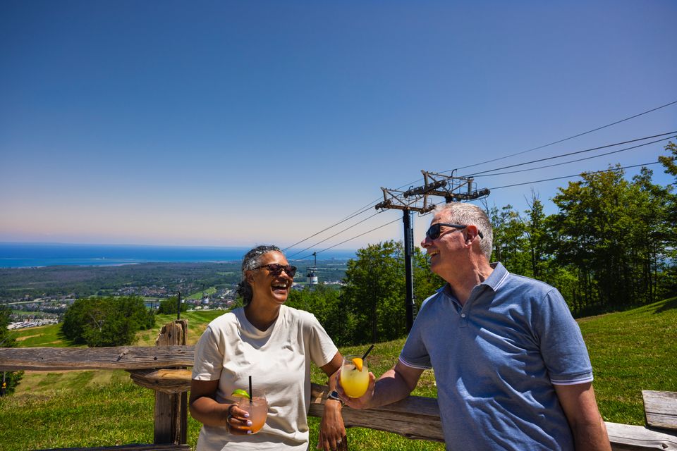 A couple enjoying fresh cocktails overlooking stunning views of the Mountain and Georgian Bay from Summitview Pavillion. 