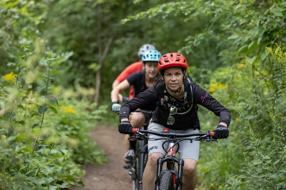 A group of friends mountain biking through the forested trails of Blue Mountain Resort Explore Park on a cool Summer afternoon.