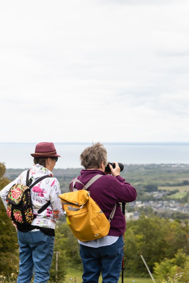 Two friends standing at the top of the Blue Mountain Resort hiking trails, taking photos of the stunning view of the South Georgian Bay.
