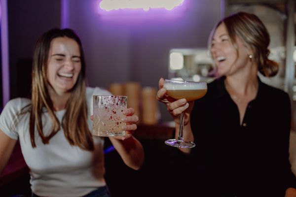 Two friends laughing and enjoying asian-inspired cocktails at Mother Tongue.